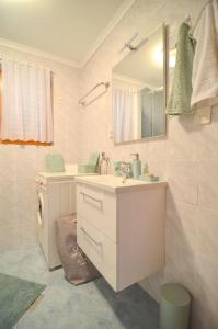 uma casa de banho branca com um lavatório e um espelho em Flower house Podčetrtek em Podcetrtek