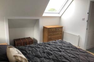 a bedroom with a bed and a dresser and a window at Seacot Cottage in the heart of the Highlands in South Kessock