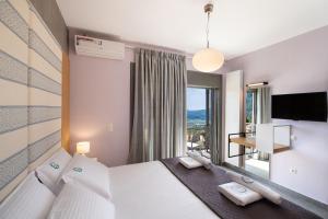 ein Hotelzimmer mit einem Bett und einem großen Fenster in der Unterkunft Aelia Suites in Áyios Pétros