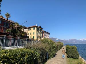 mężczyzna idący po chodniku obok wody w obiekcie Apartment Italian Charm w mieście Ghiffa