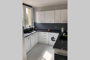 a kitchen with white cabinets and a washing machine at Apartament Sikornik in Gliwice
