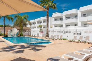 een zwembad met ligstoelen en een hotel bij Olive Beach Apartamentos in Port d'Alcudia