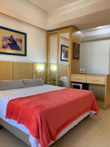 ein Schlafzimmer mit einem großen Bett mit einer roten Decke in der Unterkunft Apartamento Beverly Hills Studio in Porto Alegre