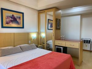 ein Schlafzimmer mit einem Bett, einem Schreibtisch und einem Spiegel in der Unterkunft Apartamento Beverly Hills Studio in Porto Alegre + 12 Fotos