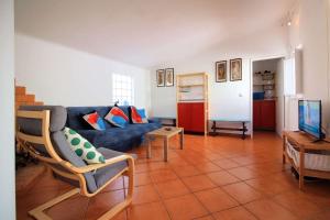 a living room with a blue couch and a tv at Casa Alentejana in Vila Nova de Milfontes