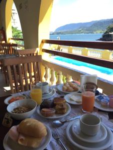 a table with plates of food and drinks on it at Colonial Hotel in Ilhabela