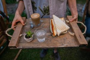 a person holding a tray with a sandwich and a drink at Pura Vida YerbaBuena Suite & Host in Yerba Buena
