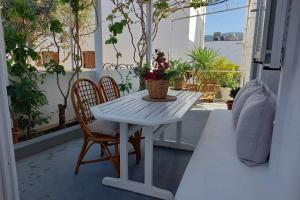 a white table and two chairs on a porch with a plant at Patmos Little Suites in Skala