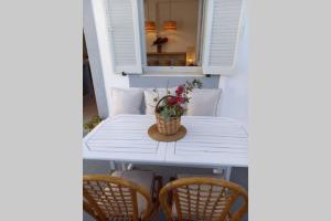 a white table with chairs and a basket of flowers at Patmos Little Suites in Skala