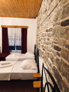 fila de camas en una habitación con pared de piedra en Stone House Obelisk, en Gjirokastra