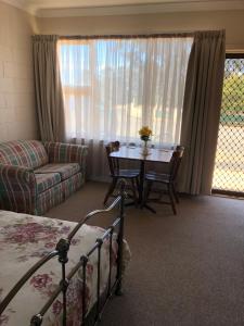 a bedroom with a bed and a table and a couch at ALPINE COUNTRY MOTEL and METRO ROADHOUSE COOMA in Cooma