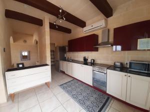 a large kitchen with white cabinets and appliances at In-Nuffara Farmhouse, Nadur Gozo in Nadur