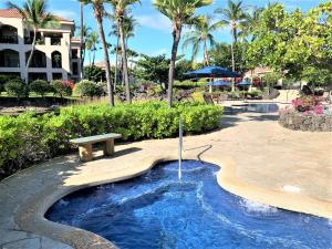 a swimming pool with a bench and an umbrella at Coconut at Shores - Waikoloa Beach Resort in Waikoloa