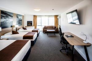 a hotel room with three beds and a desk at Mantra Bathurst in Bathurst