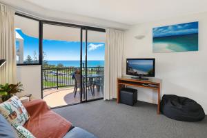 een woonkamer met televisie en een balkon bij Ocean Boulevard in Alexandra Headland