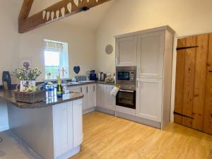 a kitchen with white cabinets and a counter top at The Byre in East Cowton