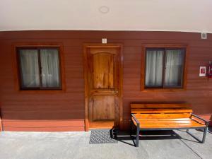 un edificio de madera con una puerta de madera y un banco en Depto N°1 Temuco Centro en Temuco