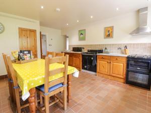 uma cozinha com uma mesa e uma mesa e cadeiras amarelas em Groes Lwyd em Gwyddelwern