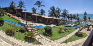 un complejo en la playa con palmeras en Pousada Enseada do Sol en Jacumã