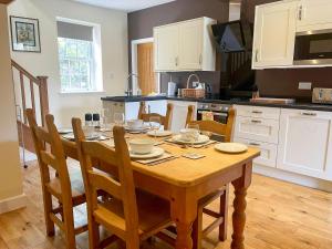 une cuisine avec une table en bois et des chaises ainsi qu'une salle à manger dans l'établissement The Coach House, à Llanrwst