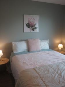 a bedroom with a white bed with two tables and two lamps at Best view on Westview in Hanmer Springs