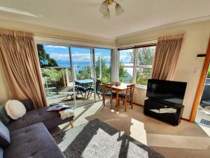 a living room with a couch and a television and a table at Kimberley One - Nelson Waterfront Apartment in Nelson