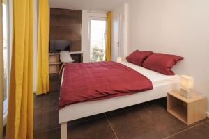 a bedroom with a bed with red sheets and a window at Designpension Classicidyll - Sennhütte 3 in Wernigerode