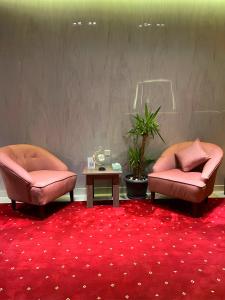 two chairs and a table on a red carpet at Mandaren Suites in Taif