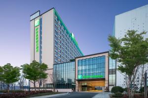 Un edificio alto con una señal verde. en Holiday Inn Zhengzhou High-Tech Zone by IHG, en Zhengzhou