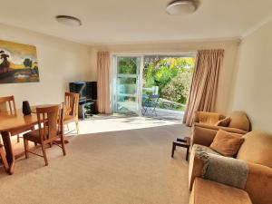 uma sala de estar com um sofá, uma mesa e cadeiras em Kimberley Two - Nelson Waterfront Apartment em Nelson