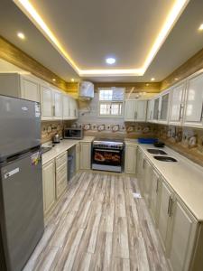 cocina con armarios blancos y suelo de madera en منتجع إطلالة السودة en Sawda