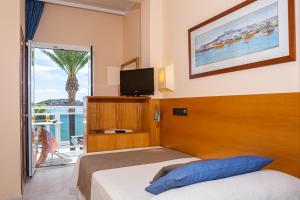 a bedroom with a bed and a tv and a balcony at Hotel Ses Figueres in Talamanca