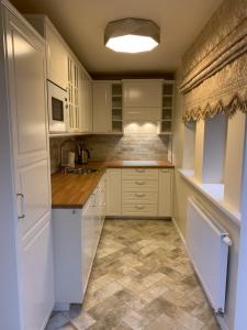 a kitchen with white cabinets and a tile floor at Vaineikio 8 in Palanga