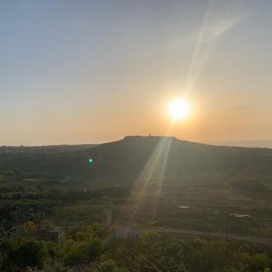 słońce zachodzące na szczycie wzgórza w obiekcie Tac-Cnic Heritage Living - Apartment, Spa Suite & Spectacular Views w mieście Żebbuġ