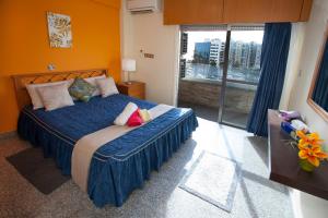 a bedroom with a bed with blue sheets and a window at Limassol Hestia Boutique Apartment in Limassol