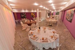 un restaurant avec des tables et des chaises blanches et des murs violets dans l'établissement Le Rex Hôtel, à Tarbes