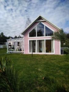 Casa rosa con ventanas grandes en un patio en Bajkowy domek Villa Rosa na Kaszubach, en Grzybowo