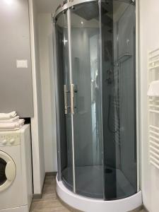 une salle de bains pourvue d'une douche en verre et d'un lave-linge. dans l'établissement Intérieurs-Cour, à Nice