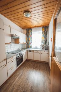 a kitchen with white cabinets and a wooden ceiling at Ferienhaus Ramsbacher in Rennweg