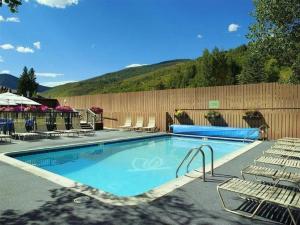 a swimming pool with chairs and a wooden fence at Wren 201 Condo with Vail Mountain View in Vail