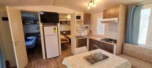 a small kitchen with a white refrigerator and a table at Mobile Homes Danijela in Amadria Park Trogir in Seget Vranjica