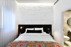 a bedroom with a large bed and a white wall at Jerusalem of concrete&stell in Jerusalem