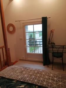 a bedroom with a window and a bed and a chair at Le clos des augers. Chambre Descartes in Azay-sur-Cher