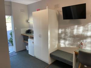 a room with a white cabinet with a tv on the wall at Camperdown Cascade Motel in Camperdown