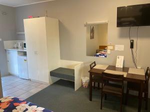 a kitchen with a table and chairs and a refrigerator at Camperdown Cascade Motel in Camperdown