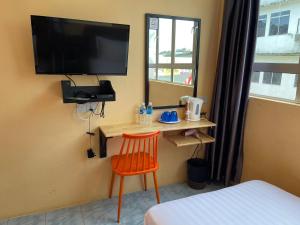 a room with a bed and a chair and a television at Loft Pals Urbanstay Lodge, Kapit in Kapit