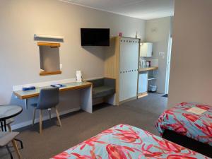 ein Hotelzimmer mit einem Schreibtisch, einem Bett und einem Bett sowie einem Schreibtisch in der Unterkunft Camperdown Cascade Motel in Camperdown