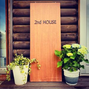 2nd House في Kitashiobara: اثنين من النباتات الفخارية تقف أمام الباب