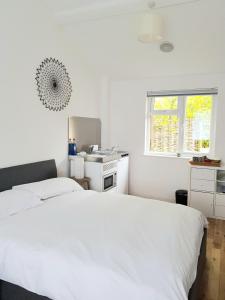 a white bedroom with a bed and a kitchen at Little Mill, Harbertonford, Totnes. - Entire place. in Totnes