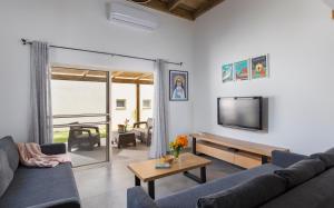 a living room with a couch and a tv at Tal Shahar Zimmers in Tal Shaẖar